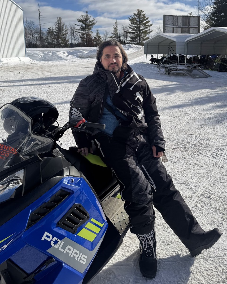 Alex Peysakhovich sitting on a snowmobile in the snow